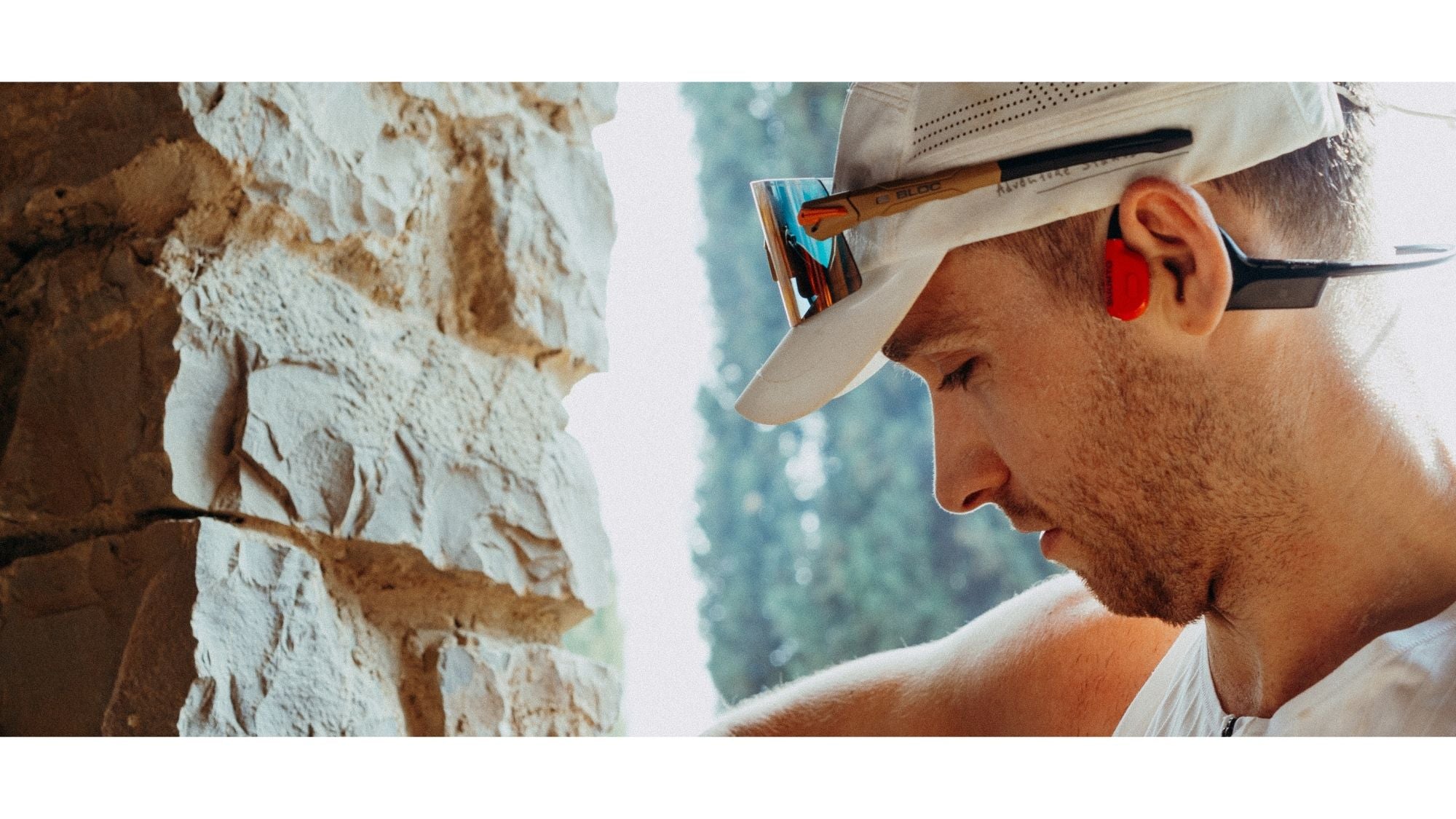Man wearing a hat and sunglasses with a scenic background